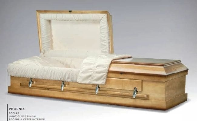 A closed wooden casket with white interior lining.