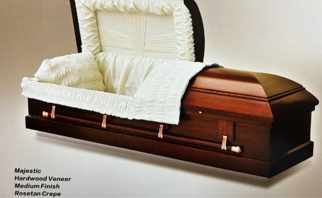 An open wooden coffin with a white cushioned interior.