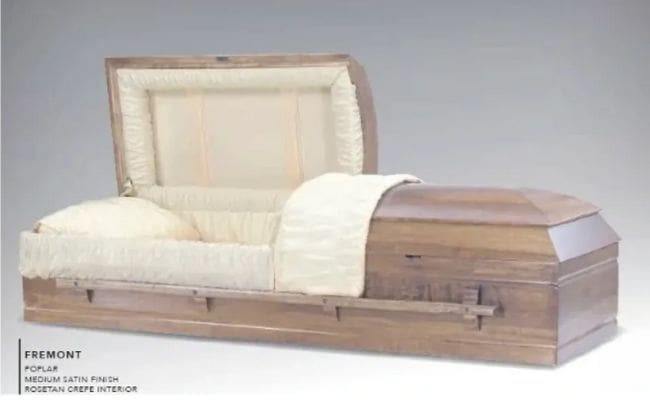 A partially open wooden coffin with a cream-colored interior lining.