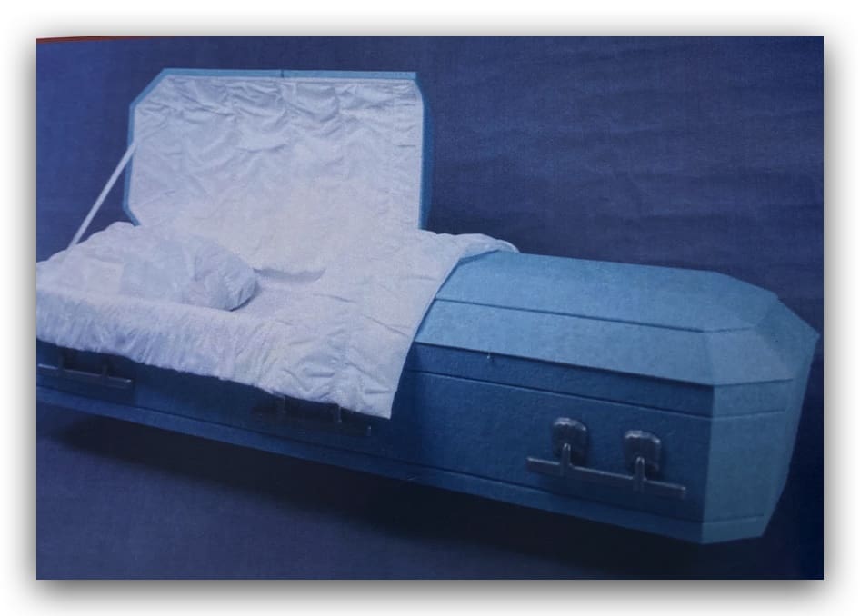 A blue casket with a white pillow inside, placed on a dark surface.