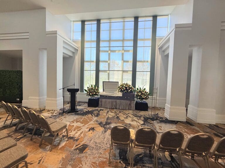 Viewing setup at the California Center for the Arts, Escondido, with a casket, flower arrangements and rows of chairs