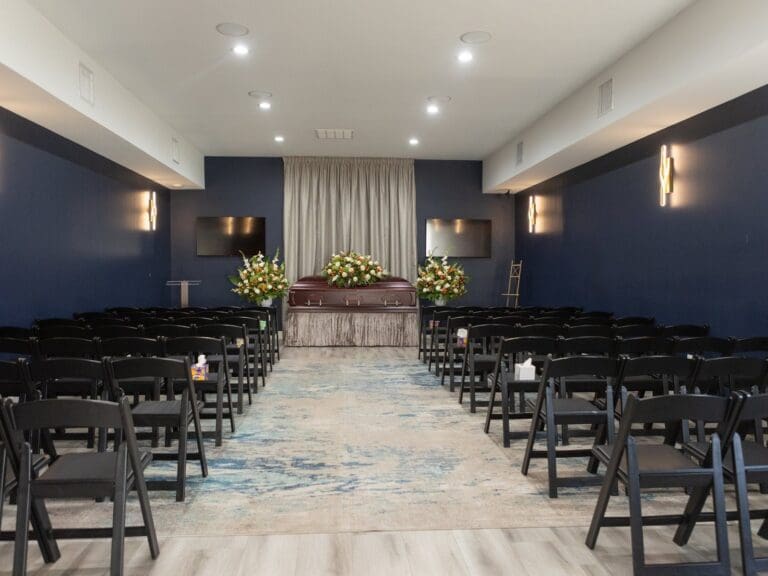 Silver Lining chapel with blue walls, rows of chairs and a casket with flowers at the front